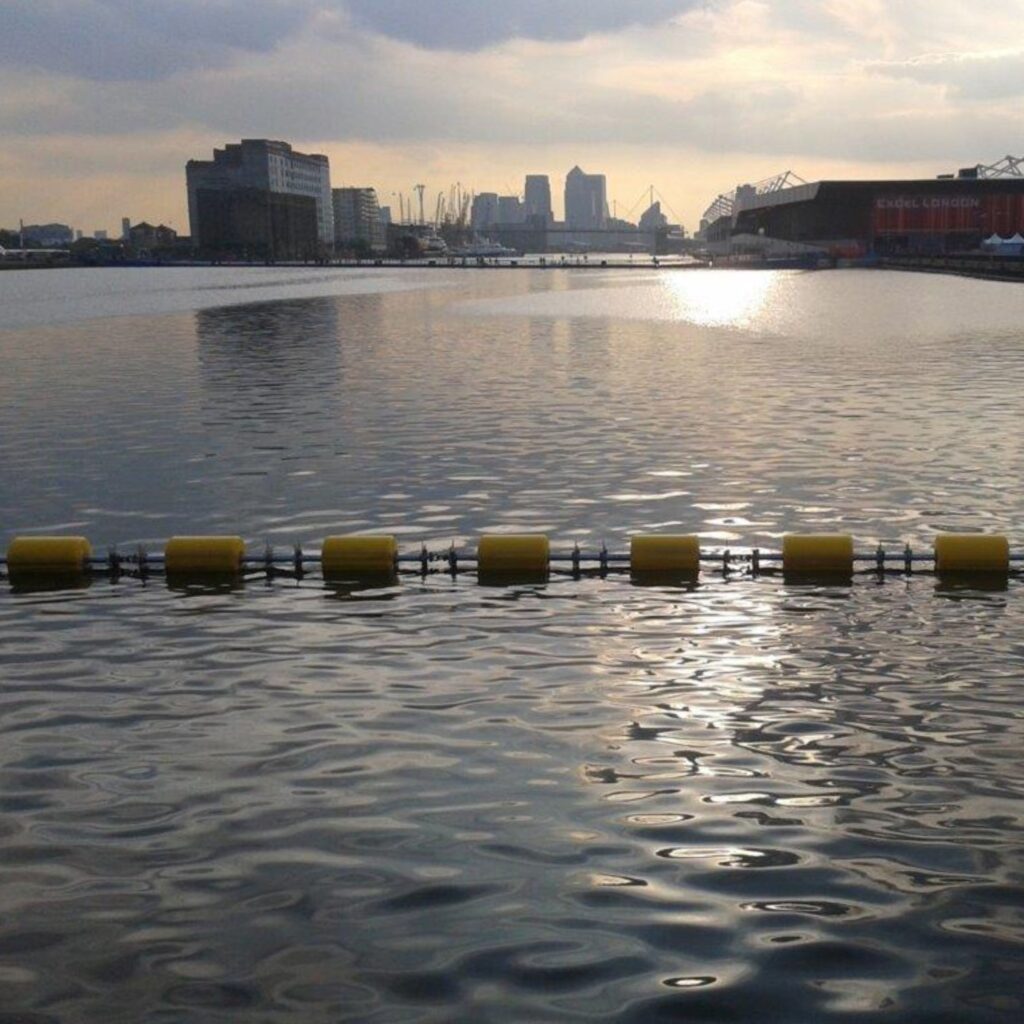 Sistema DMS Boom con flotadores amarillos instalado en zona portuaria para protección perimetral