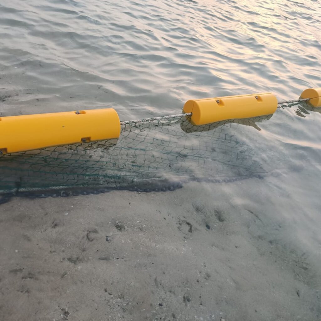 Bolina Shark Safety Net Boom en aguas poco profundas, con red selectiva y flotadores visibles para protección en playas naturales
